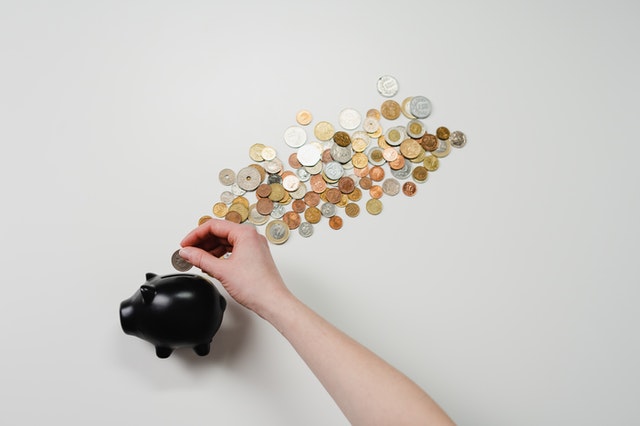 Cofre de porquinho com várias moedas num fundo branco